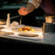 Un chef cuisinier en pleine préparation d'un plat gastronomique sophistiqué, utilisant des ingrédients frais et locaux, illustrant l'engagement de Bevanar & Dorga envers la qualité des produits pour les professionnels de la restauration.