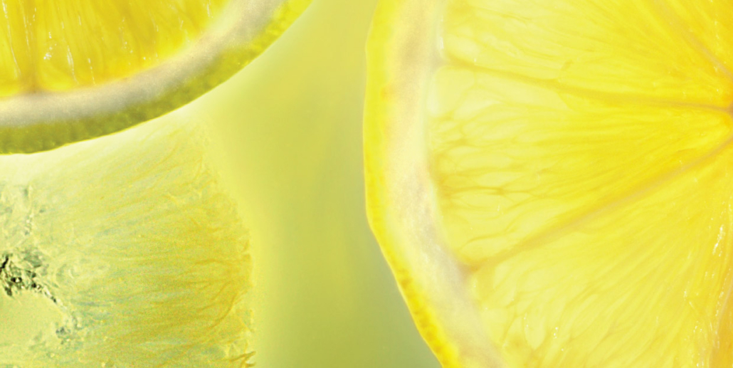 Un gros plan lumineux de tranches de citron jaune translucide, avec leurs détails texturés visibles, baignant dans une lumière verte et jaune douce.